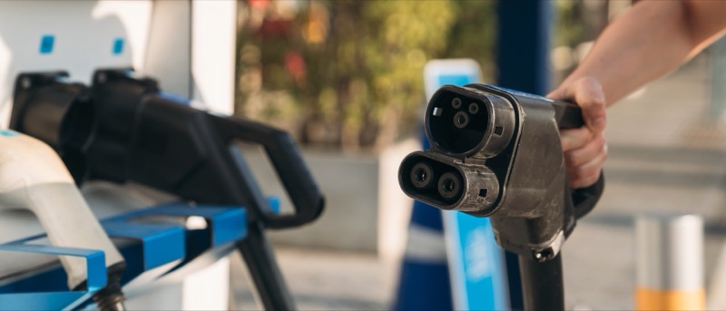 Hand plugging in an EV charger connector — using proper cables for safe charging