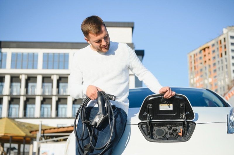 Mann lädt Elektroauto an öffentlicher Schnellladestation unterwegs