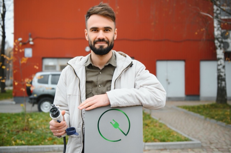 Man holding an EV charger plug while planning home installation costs